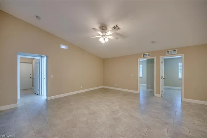 Tiled empty room with ceiling fan and vaulted ceiling