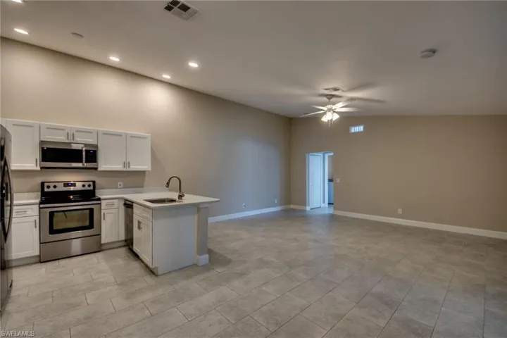 Kitchen featuring appliances with stainless steel finishes, ceiling fan, sink, light tile patterned flooring, and kitchen peninsula