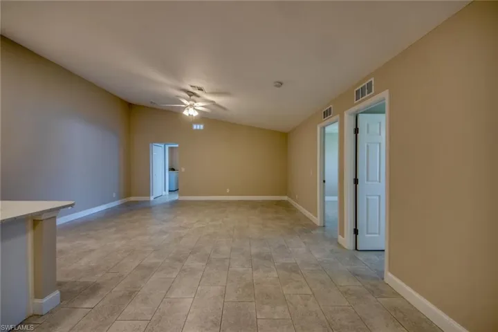 Unfurnished living room featuring ceiling fan, vaulted ceiling, and light tile patterned floors