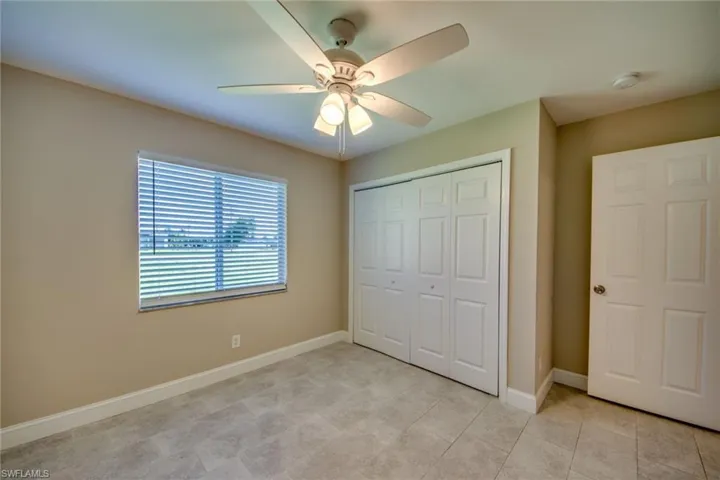 Unfurnished bedroom with ceiling fan, light tile patterned flooring, and a closet