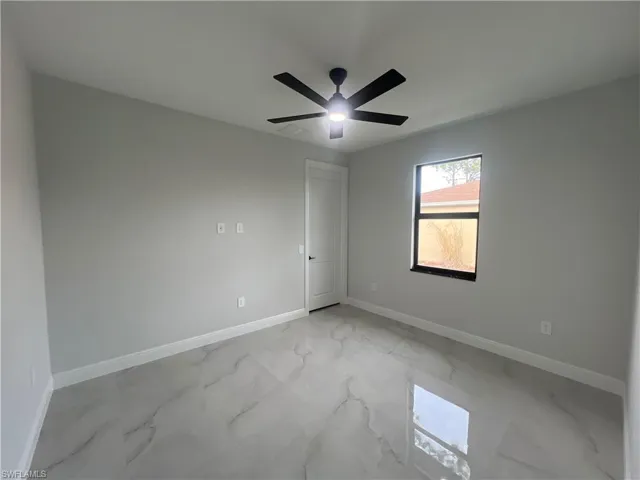 2nd bed room with light marble finish floors and ceiling fan