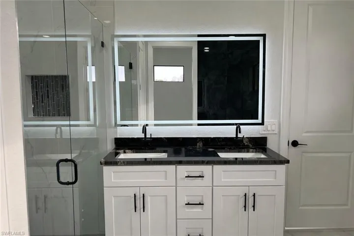 Bathroom featuring a marble finish shower and double vanity