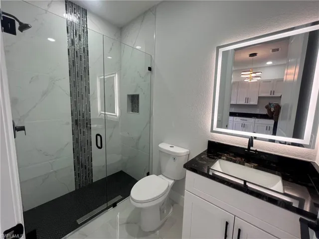 In law Full bathroom featuring a textured wall, vanity, a marble finish shower, and recessed lighting