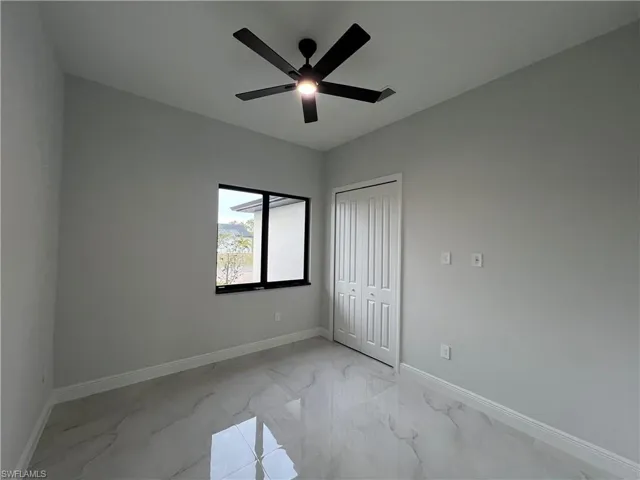 3rd bedroom, unfurnished with light marble finish floors, a closet, and a ceiling fan