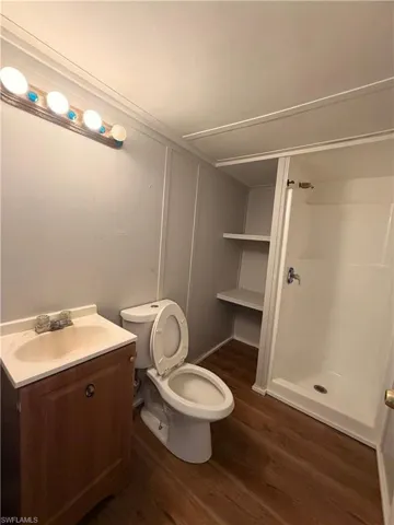 Bathroom featuring a shower stall, vanity, and dark wood-style floors