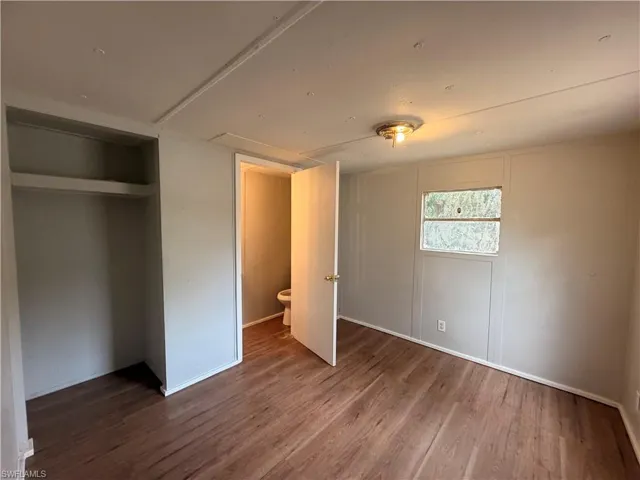 Unfurnished bedroom featuring dark wood finished floors and a closet