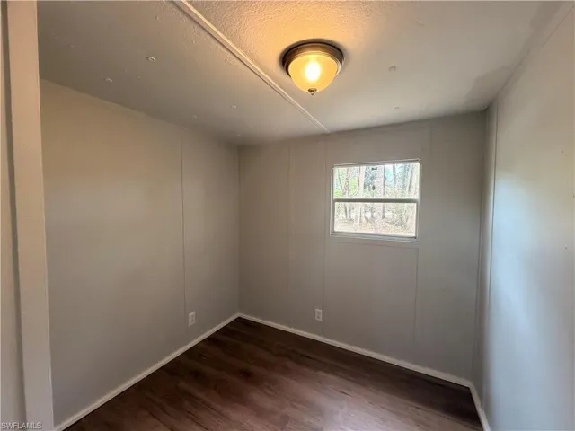 Spare room with dark wood finished floors, a decorative wall, and a textured ceiling