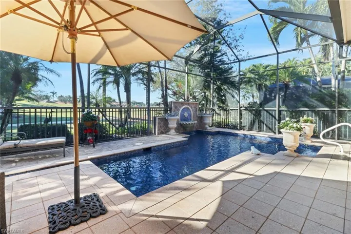View of patio / terrace with an outdoor stone fireplace, pool water feature, ceiling fan, and a lanai