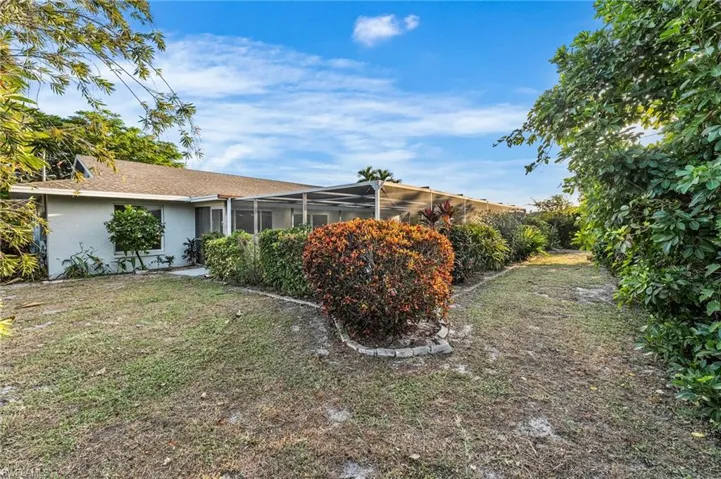 Back View of green lawn featuring a lanai and a sunroom