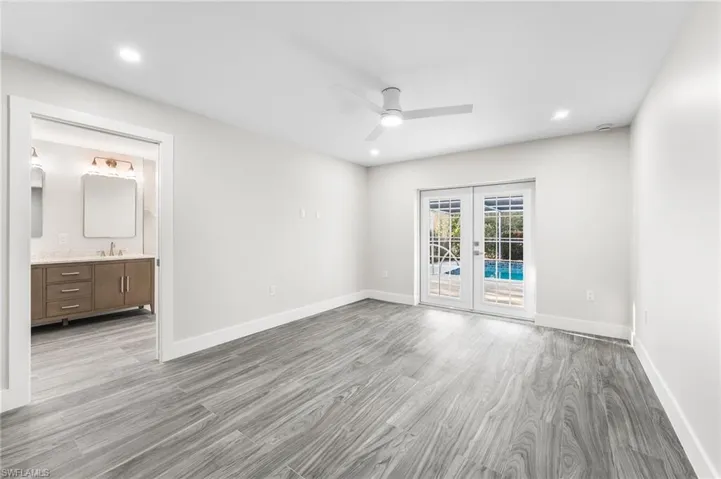 Master Bedroom featuring French doors, light wood-style tile floors, ceiling fan, and recessed lighting.  Master bath off the bedroom