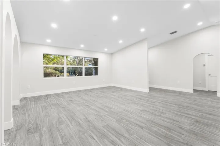 Living room and entry featuring arched areas, recessed lighting, and light wood-tile floors