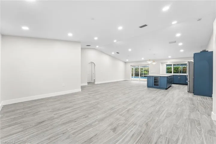 Living room featuring vaulted ceiling, recessed lighting, and light wood-tile floors