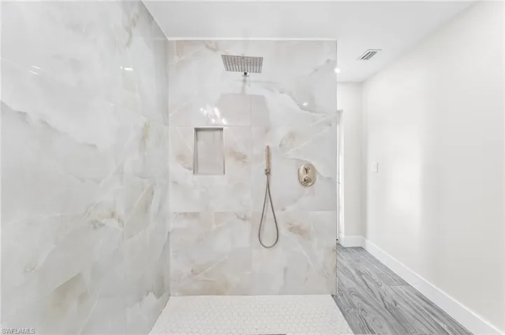 Full bathroom with a marble finish shower, wood tile finished floors, and recessed lighting.  Pool bath entrance.