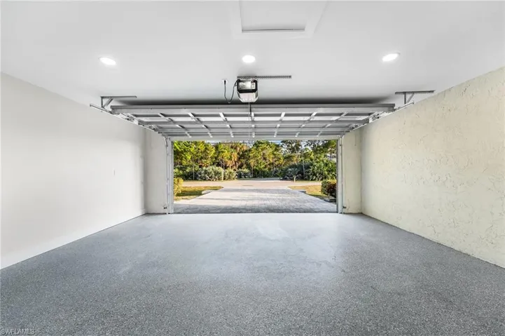 Garage with a textured wall, recessed lighting, and a garage door opener.  New garage door and epoxy flooring.