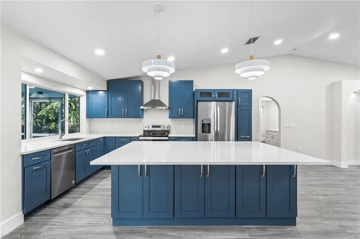 Kitchen with blue cabinetry, decorative light fixtures, stainless steel appliances, a center island, and recessed lighting