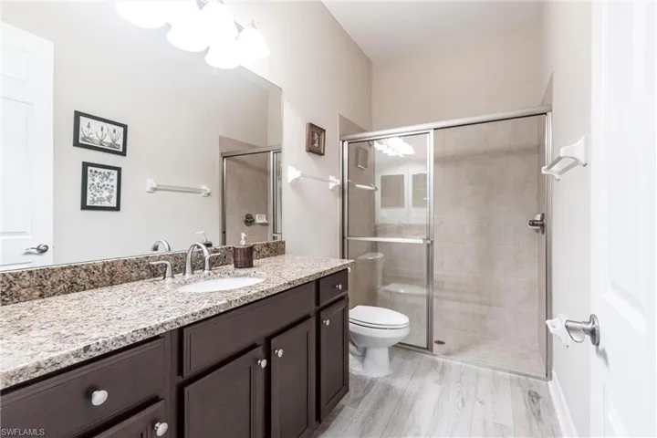 Bathroom with walk in shower and bright lighting with newly installed flooring.