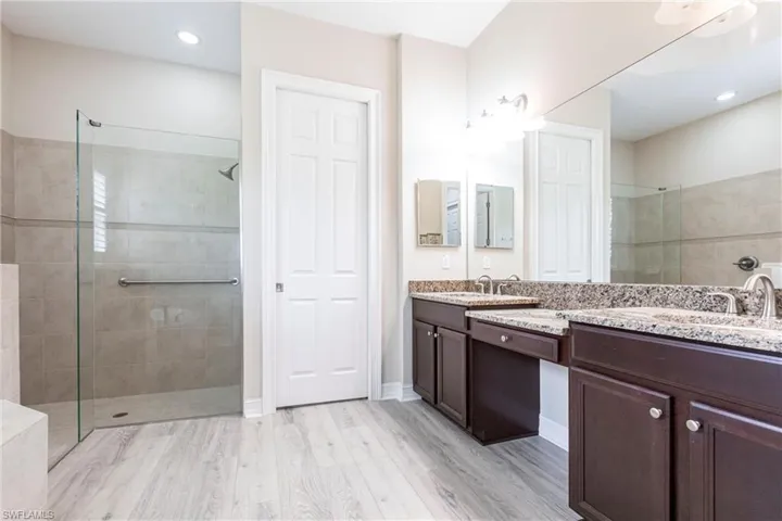 Bathroom featuring large walk in tiled shower, vanity, hardwood / wood-style flooring.