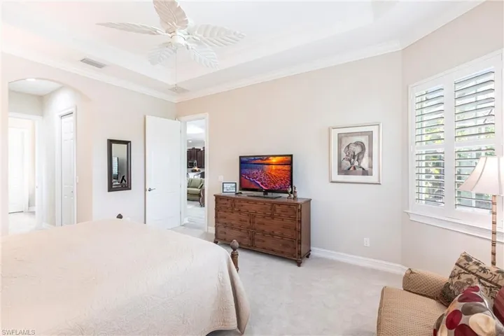 View of Master Bedroom to Family room area with plantation shutters, ceiling fan and view of Lake.