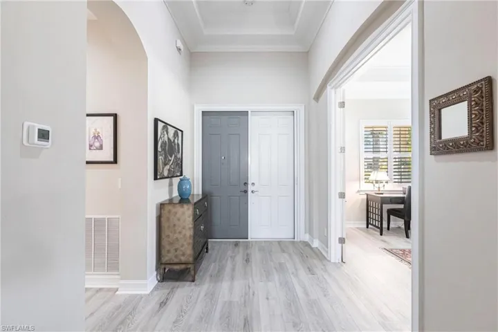 View of Foyer towards front door with light wood-style floors, raised ceiling and easy access to Den.