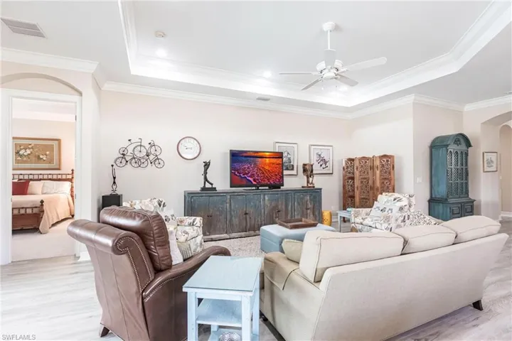 Open feel throughout home with bedrooms, kitchen, dining and Lanai area adjacent to Large Family room. Family room with crown molding, ceiling fan, light wood-type flooring, and a tray ceiling