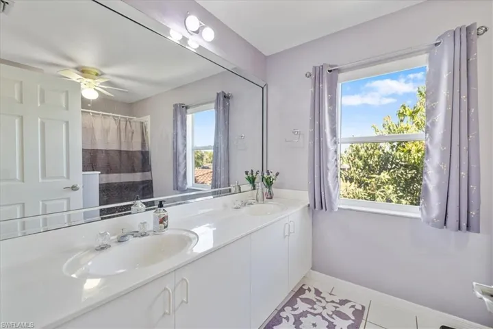 Bathroom with baseboards, double vanity, a sink, and tile patterned flooring