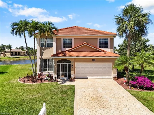 Mediterranean / spanish-style house featuring a water view, a tiled roof, decorative driveway, a front yard, and stucco siding