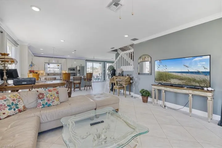 Living room with light tile patterned flooring, ornamental molding, recessed lighting, and visible vents