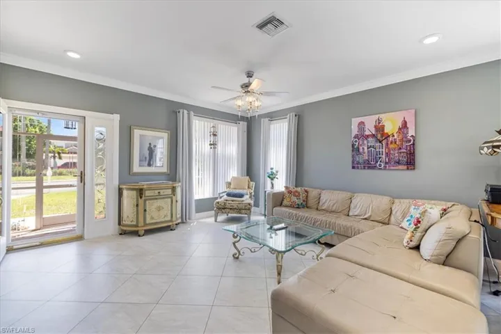 Living room featuring light tile patterned flooring, ornamental molding, visible vents, ceiling fan, and recessed lighting