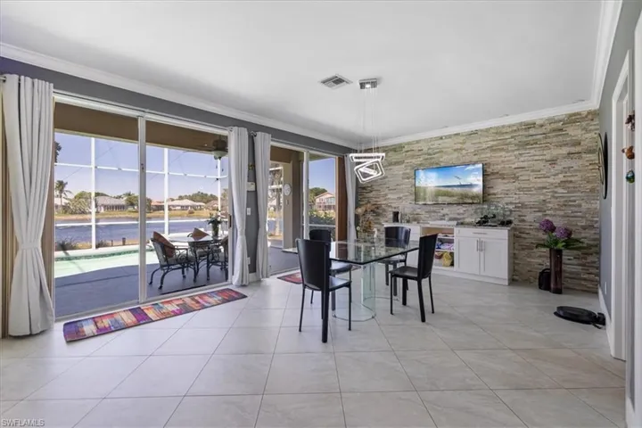 Dining room featuring light tile patterned floors, ornamental molding, a water view, and visible vents