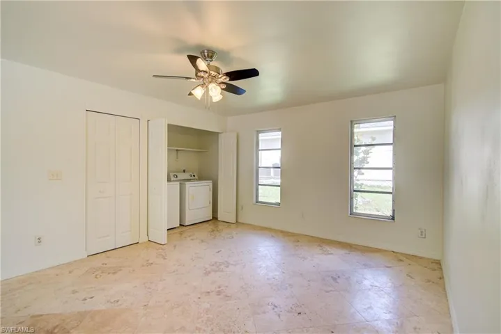 Unfurnished bedroom featuring washer and clothes dryer, multiple closets, and a ceiling fan