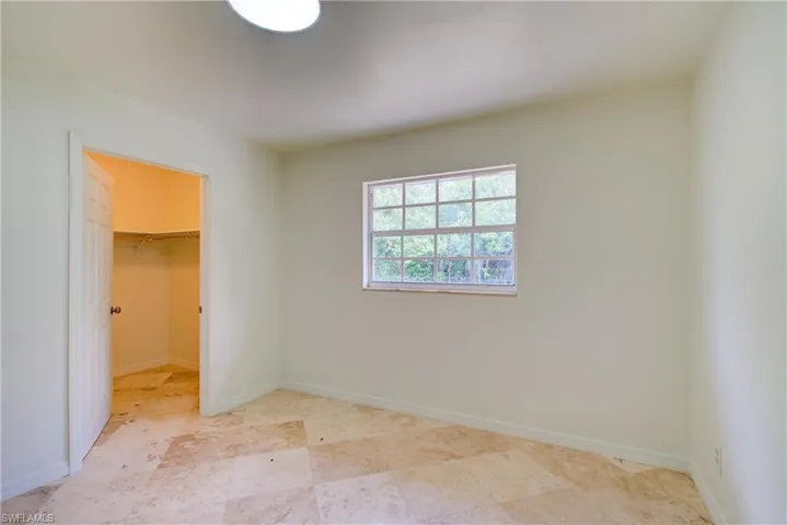 Unfurnished bedroom featuring a walk in closet and a closet