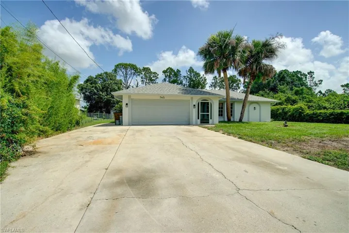 View of front of home with an attached garage, stucco siding, a front yard, and driveway