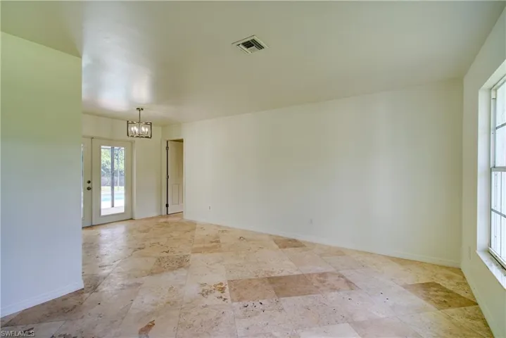 Empty room featuring a chandelier and light stone finish flooring