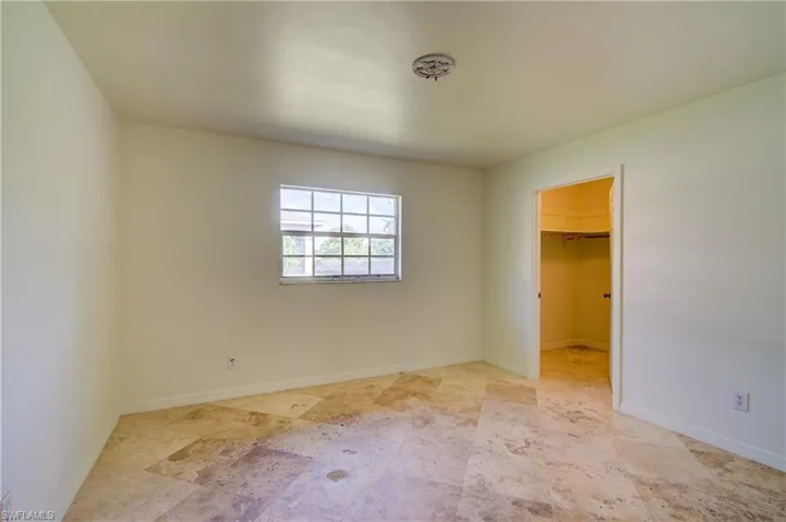 Unfurnished bedroom with a spacious closet, a closet, and stone finish floors