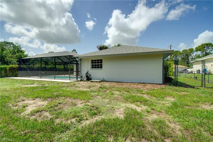Rear view of house with stucco siding and glass enclosure