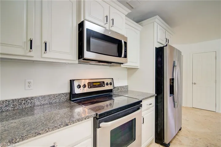 Kitchen featuring appliances with stainless steel finishes and white cabinetry