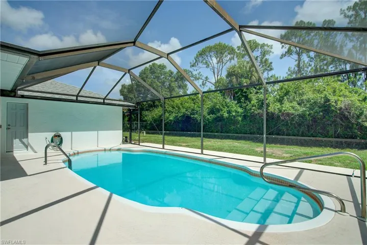 Swimming pool with a patio area, a lawn, and glass enclosure