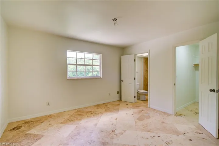 Unfurnished bedroom with a spacious closet, connected bathroom, and a closet