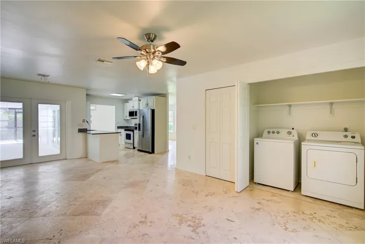 Washroom featuring separate washer and dryer, a ceiling fan, french doors, and healthy amount of natural light