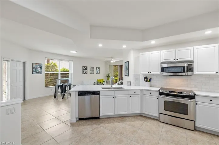 Kitchen featuring sink, appliances with stainless steel finishes, ceiling fan, backsplash, and white cabinets