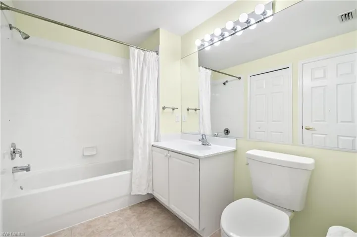 Full bathroom featuring toilet, vanity, shower / bath combination with curtain, and tile patterned flooring