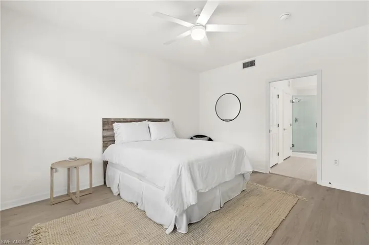 Bedroom with ensuite bath, light hardwood / wood-style floors, and ceiling fan