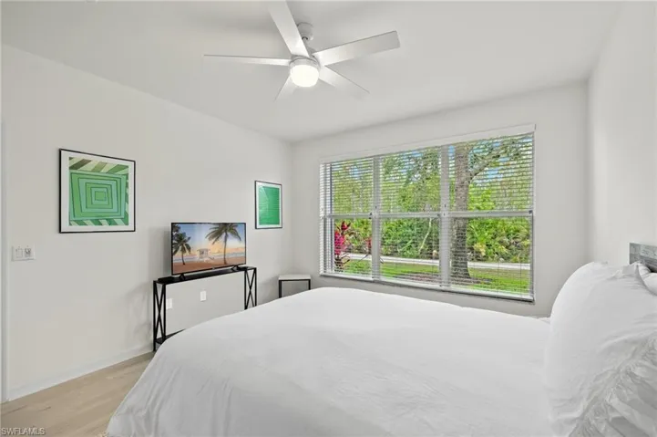 Bedroom with ceiling fan, multiple windows, and light wood-type flooring