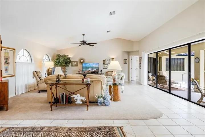 Carpeted living room with ceiling fan and vaulted ceiling