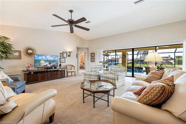 Living room featuring lofted ceiling, ceiling fan, light colored carpet, and a healthy amount of sunlight