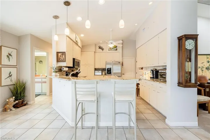 Kitchen with appliances with stainless steel finishes, hanging light fixtures, white cabinetry, and ceiling fan