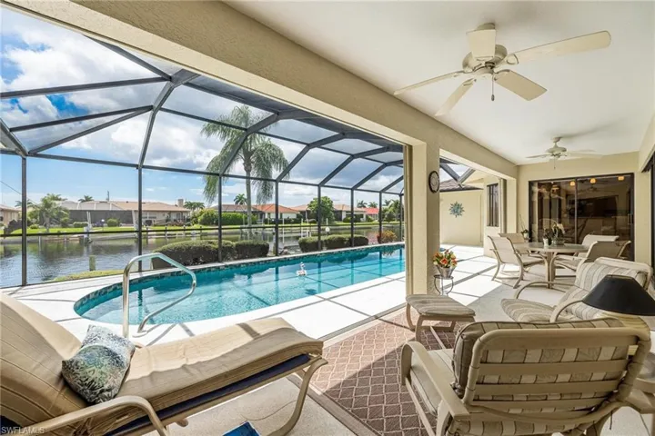 View of swimming pool with a patio, a water view, a lanai, and ceiling fan