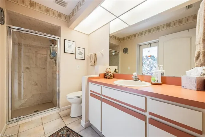 Bathroom featuring tile patterned flooring, vanity, toilet, and a shower with shower door