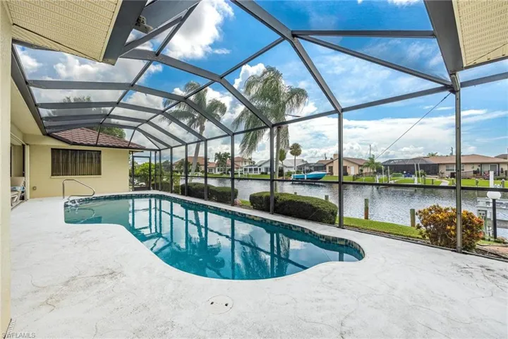 View of swimming pool featuring a patio, glass enclosure, and a water view