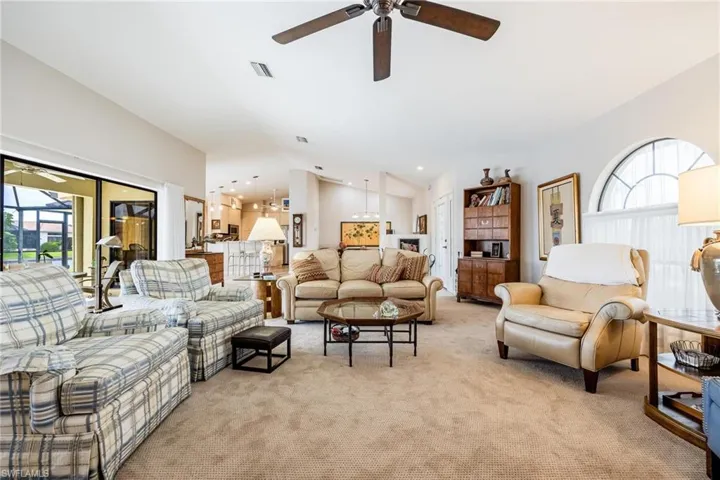 Living room featuring ceiling fan, light carpet, vaulted ceiling, and a wealth of natural light